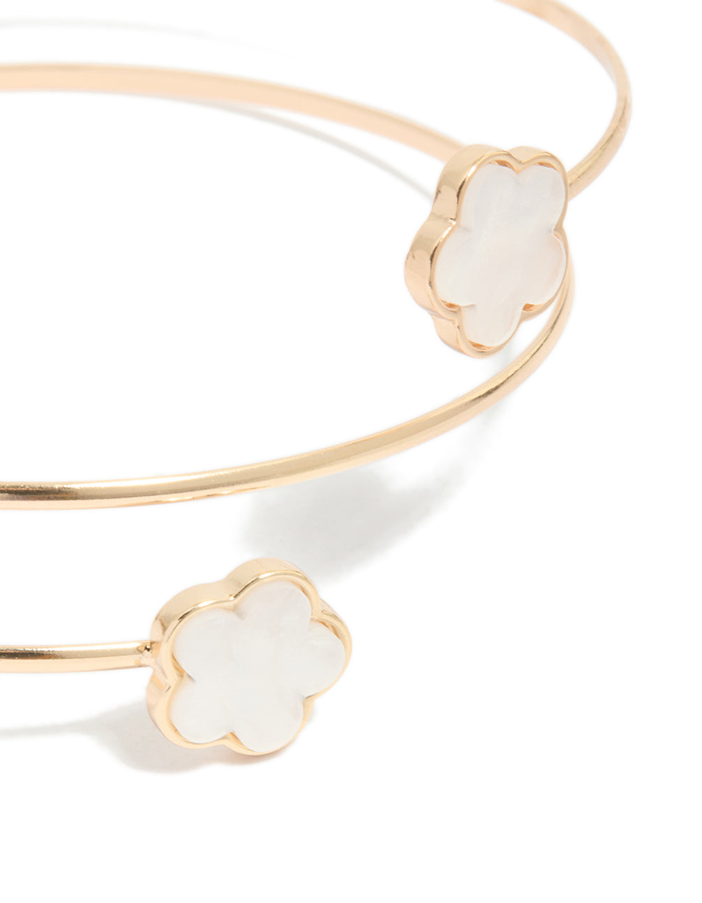 A gold small flower arm cuff with white floral details in close up view