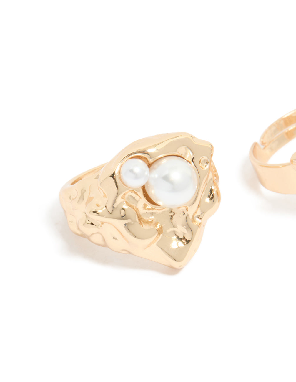 Close-up of brushed gold ring with pearl embellishment and ornate band design detail view