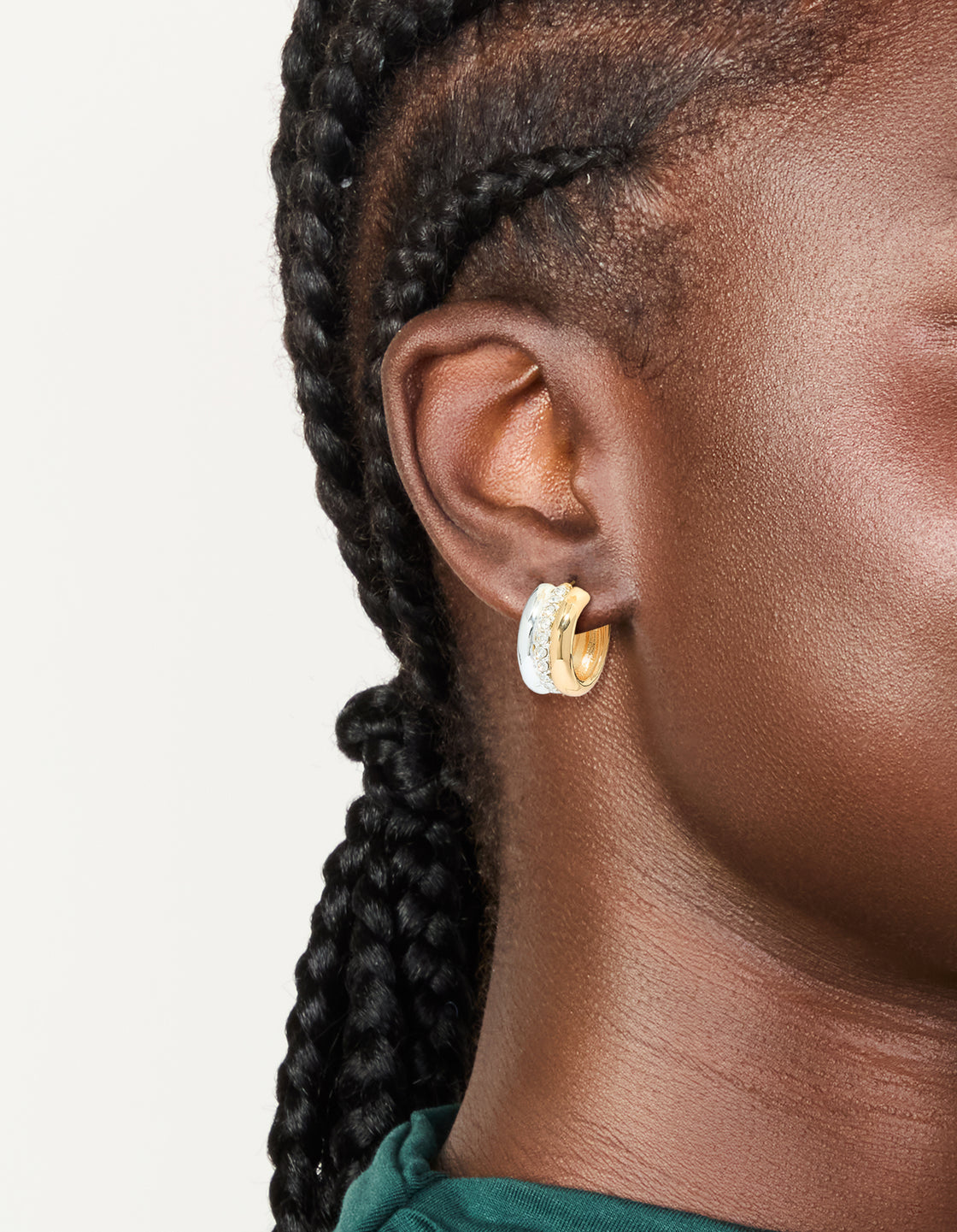 Showcasing mixed metal plated cubic zirconia detailed huggie earrings in gold, silver, and white on ear view