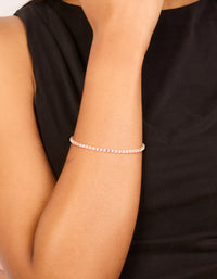 Showcasing a gold pink cubic zirconia dainty tennis bracelet in light pink on wrist view - link has visual effect only