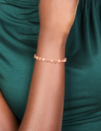 Stunning bracelet featuring light pink and hot pink cubic zirconia in a dainty gold design on wrist view - link has visual effect only