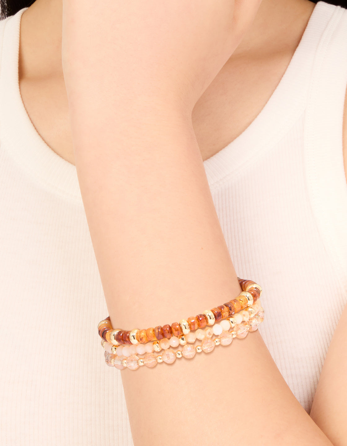 Showcasing clear and brown beaded stretch bracelets in a 3-pack with gold accents on wrist view