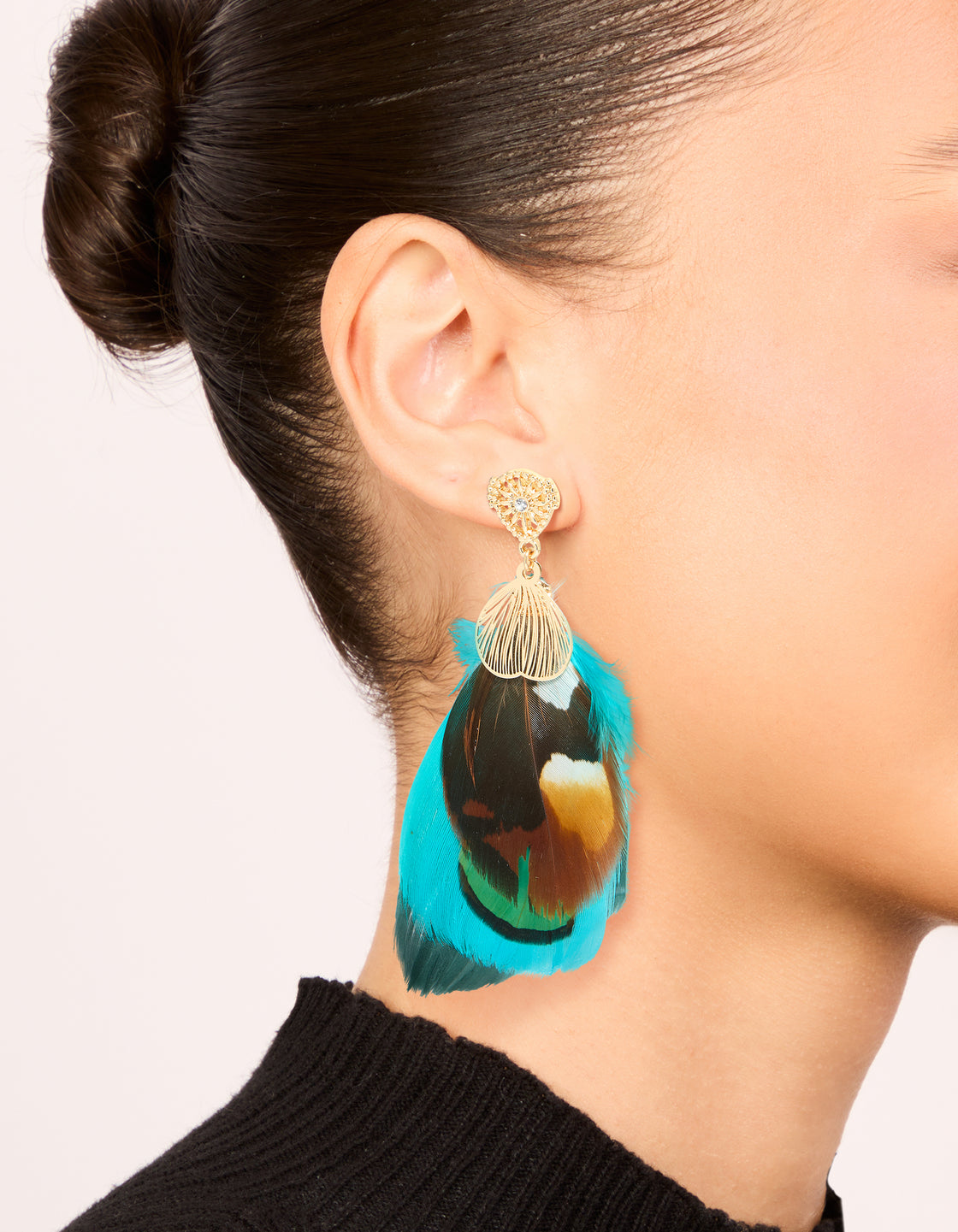 Discover statement drop earrings in gold with feather details and turquoise, brown accents on ear view