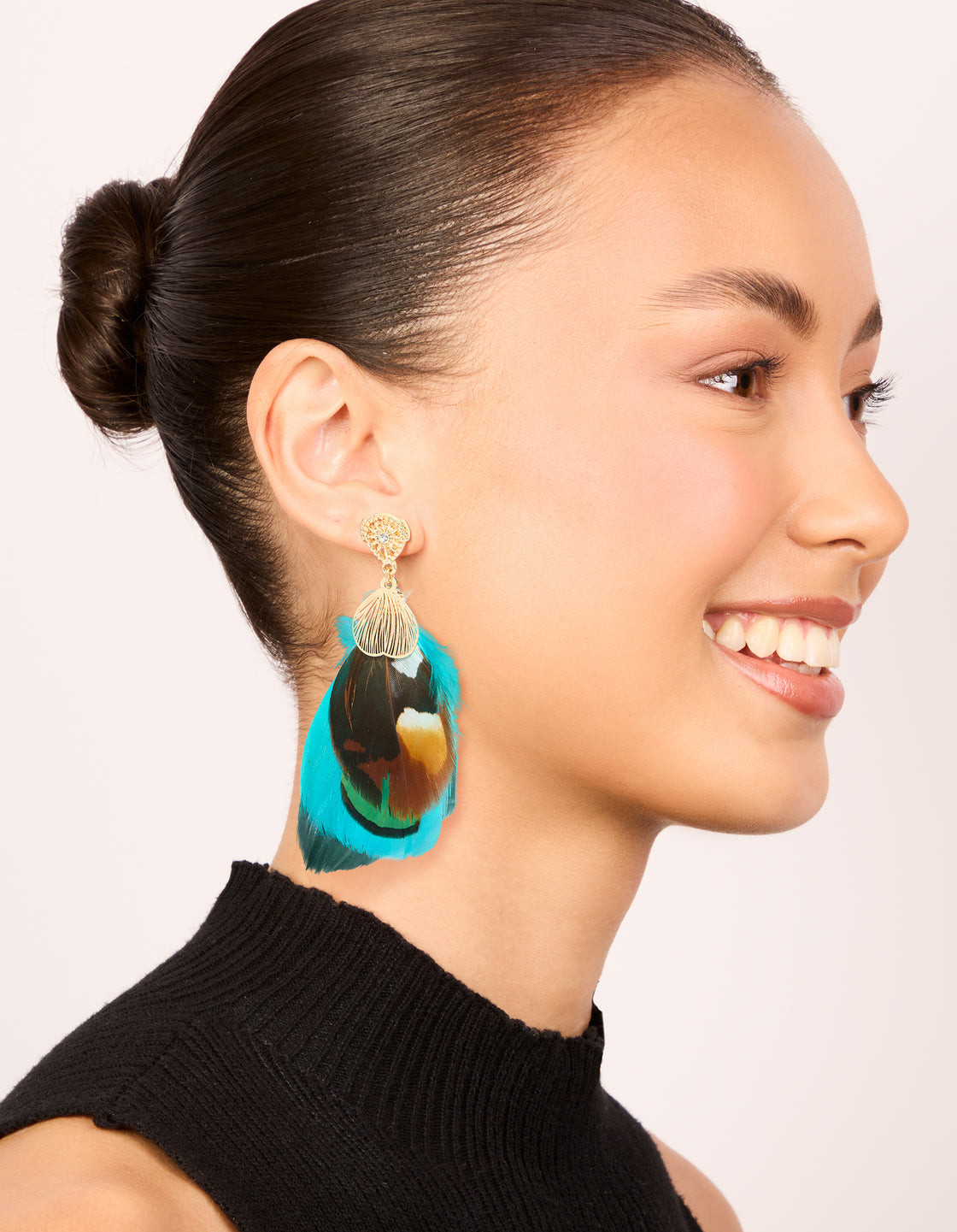 Crafted with statement feather drop earrings in gold, turquoise, and brown on model view