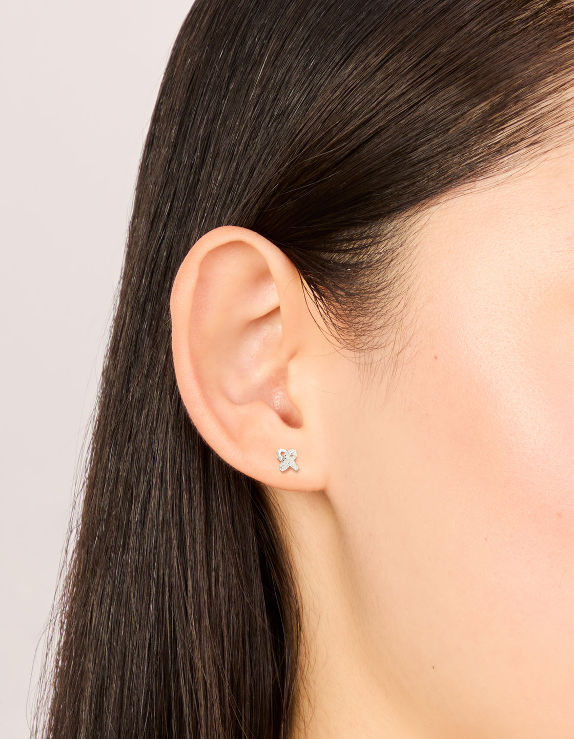 Showcasing sterling silver cubic zirconia knot stud earrings with clear accents in a on ear view