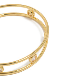 Showcasing a statement bangle in gold plated brass with bezel set cubic zirconia stones and wrist cuff styling close up view - link has visual effect only
