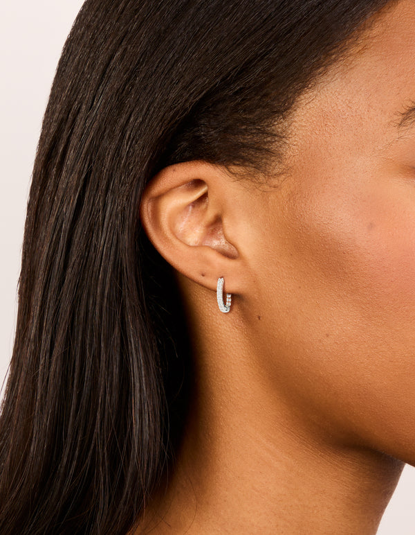 Discover skinny huggie earrings in silver plated finish with cubic zirconia on ear view