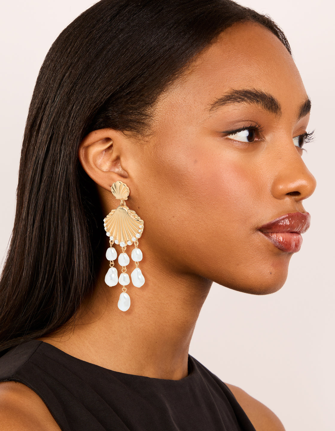 Crafted with gold ribbed shell and pearls charm drop earrings featuring ocean theme in statement style on model view