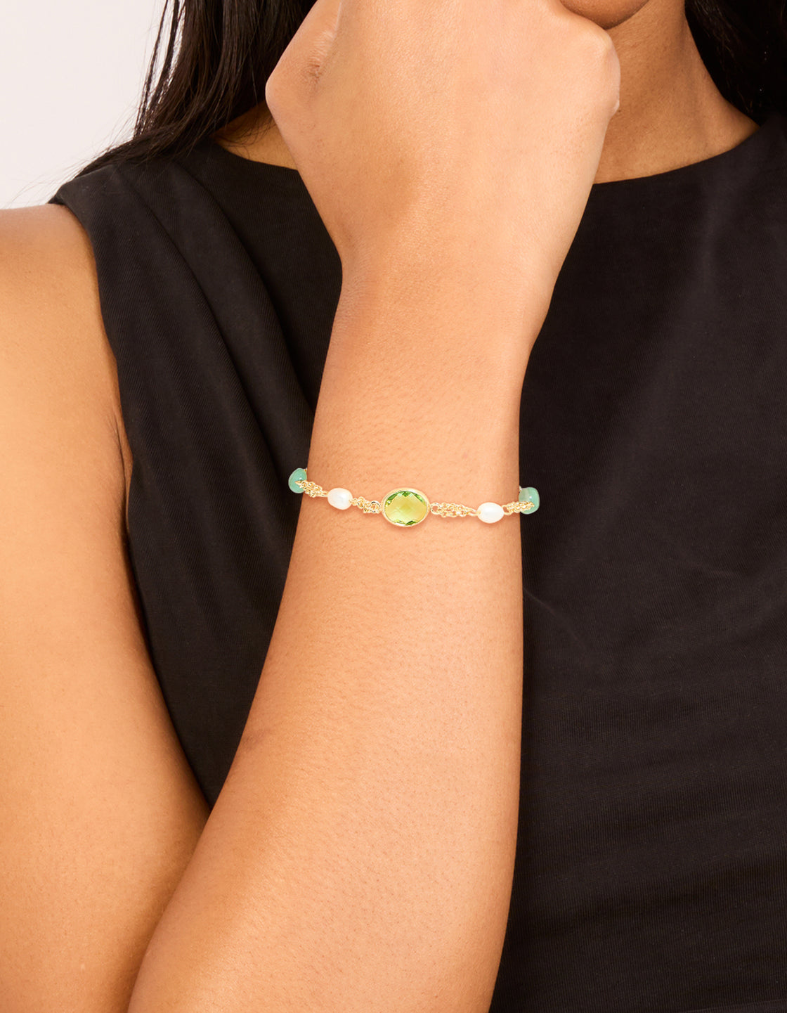 Showcasing a gold plated green cubic zirconia freshwater pearl toggle bracelet with beads, on wrist view