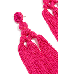 Designed with hot pink fabric, these statement drop earrings showcase beads and tassel elements close up view - link has visual effect only