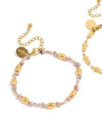 Detailed view of waterproof bracelets in a 2-pack with ocean accents, crafted from stainless steel, one featuring beads on pink and blue cord and one in gold plated finish close up view - link has visual effect only