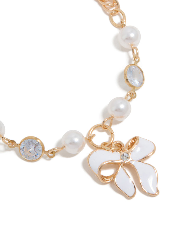Featuring a gold statement bracelet with bow charm and pearl details close up view
