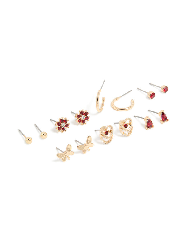 Discover stud earrings in a 7-pack featuring butterfly, floral, heart, and ball designs with red diamante accents and gold finish front view