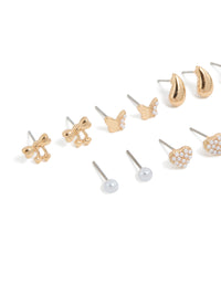 Crafted from gold with mini bow, celestial star, ball, heart, and pearl stud earrings in a 7-pack close up view - link has visual effect only