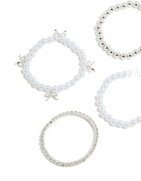 Detailed view of kids beaded stretch bracelets with bow charm accents and pearl elements in silver tones close up view - link has visual effect only