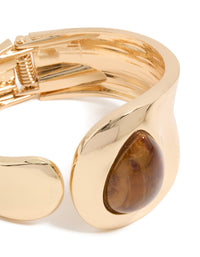 Showcasing a gold teardrop brown stone wrist cuff in statement style close up view - link has visual effect only
