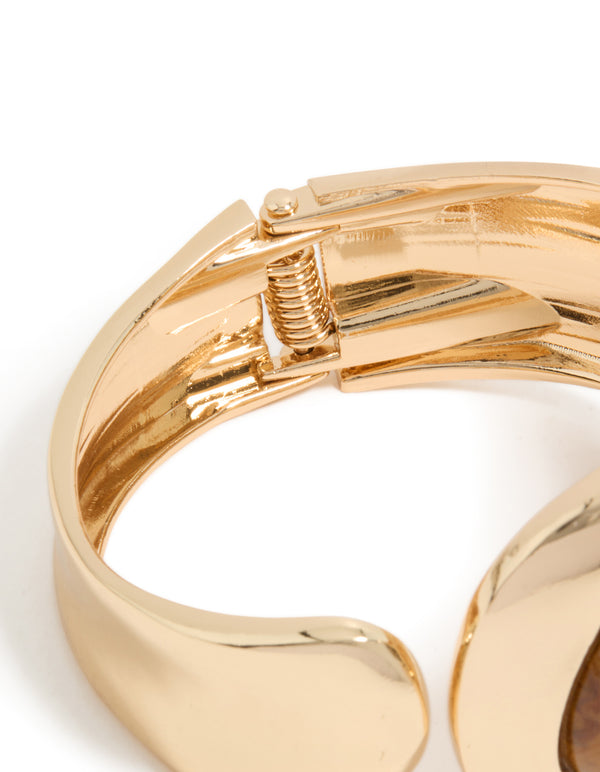 Highlighting a gold teardrop brown stone wrist cuff in statement style closure detail view