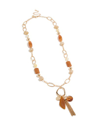 Explore this long beaded necklace with balls, beads, charm elements, and tassel fringe in gold statement styling front view - link has visual effect only