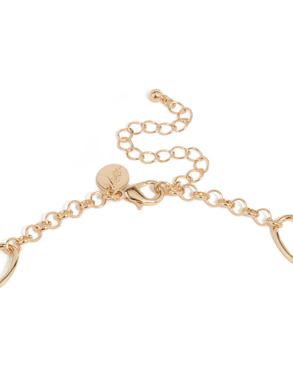 Highlighting the long beaded necklace with balls, beads, charm accents and tassel fringe in gold statement style clasp detail view