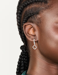 Featuring silver plated cubic zirconia flower huggie drop earrings in dainty hoop closure on ear view - link has visual effect only
