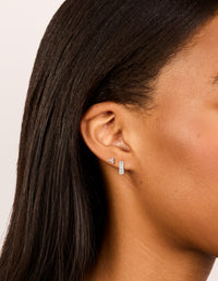 Showcasing silver plated cubic zirconia trio stud and huggie earrings in a 2-pack on ear view - link has visual effect only