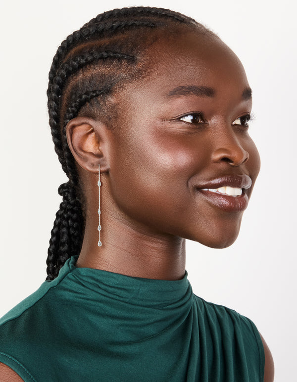 Featuring station threader earrings with pear cut cubic zirconia in silver plated finish on model view