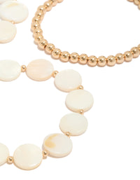 Crafted with gold beads and genuine shell discs in ivory and beige tones, these 4-pack bracelets highlight ocean-inspired design detail view - link has visual effect only