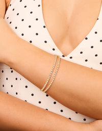 Stylish thin double cubic zirconia tennis toggle bracelet in gold plated finish on wrist view - link has visual effect only