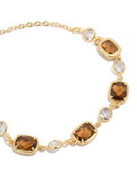Highlighting a gold plated clear and cognac cubic zirconia square cut bezel toggle bracelet close up view - link has visual effect only