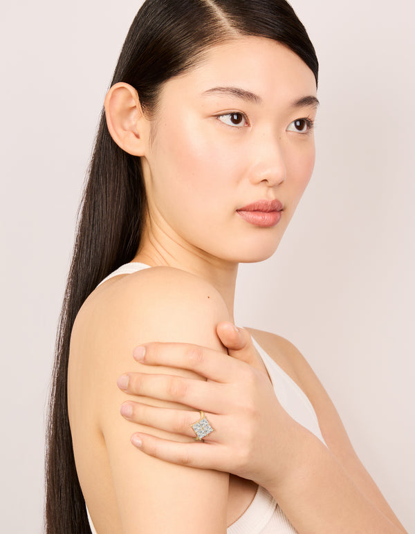 Showcasing a gold plated statement ring with cubic zirconia textured square design in clear on finger view