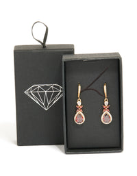 Showcasing statement drop earrings crafted from cubic zirconia with dark red teardrop stones surrounded by clear crystals in a gold setting, front view - link has visual effect only