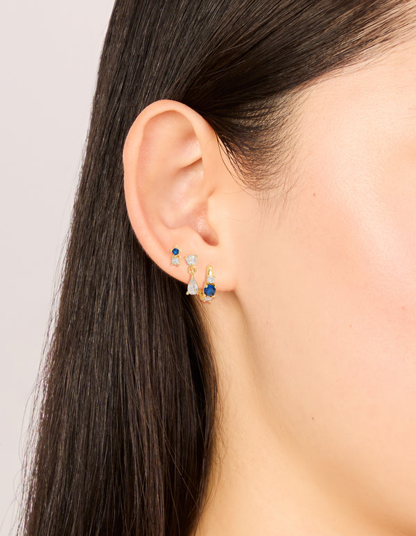 Showcasing gold plated mixed cut blue cubic zirconia mini earrings 3-pack with crystal and huggie closure on ear view