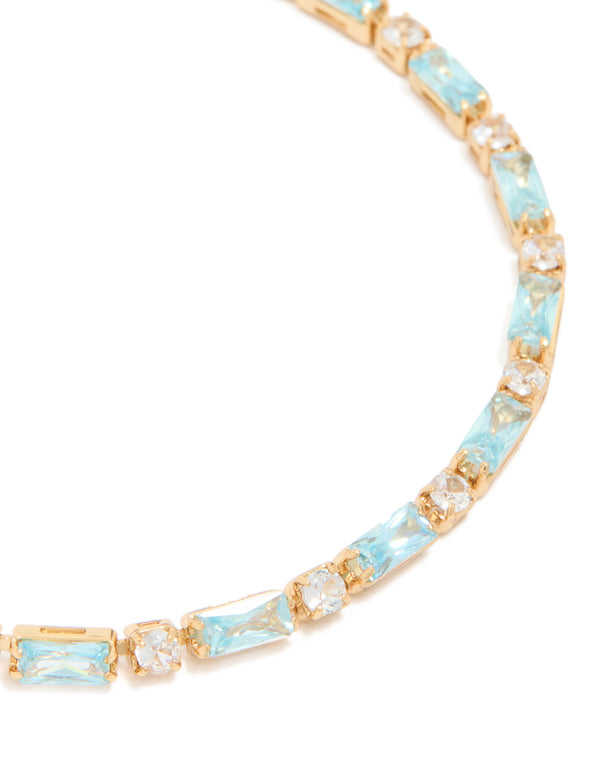 Showcasing a gold plated toggle bracelet with clear and aqua baguette cut cubic zirconia stones close up view
