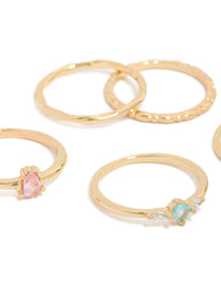 Showcasing gold plated rings with solitaire and oval stone cut cubic zirconia in pink and blue crystal close up view - link has visual effect only
