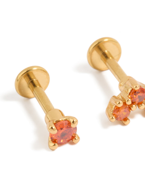 Presenting titanium stud earrings crafted from gold plated metal with flat back closure and red cubic zirconia close up view