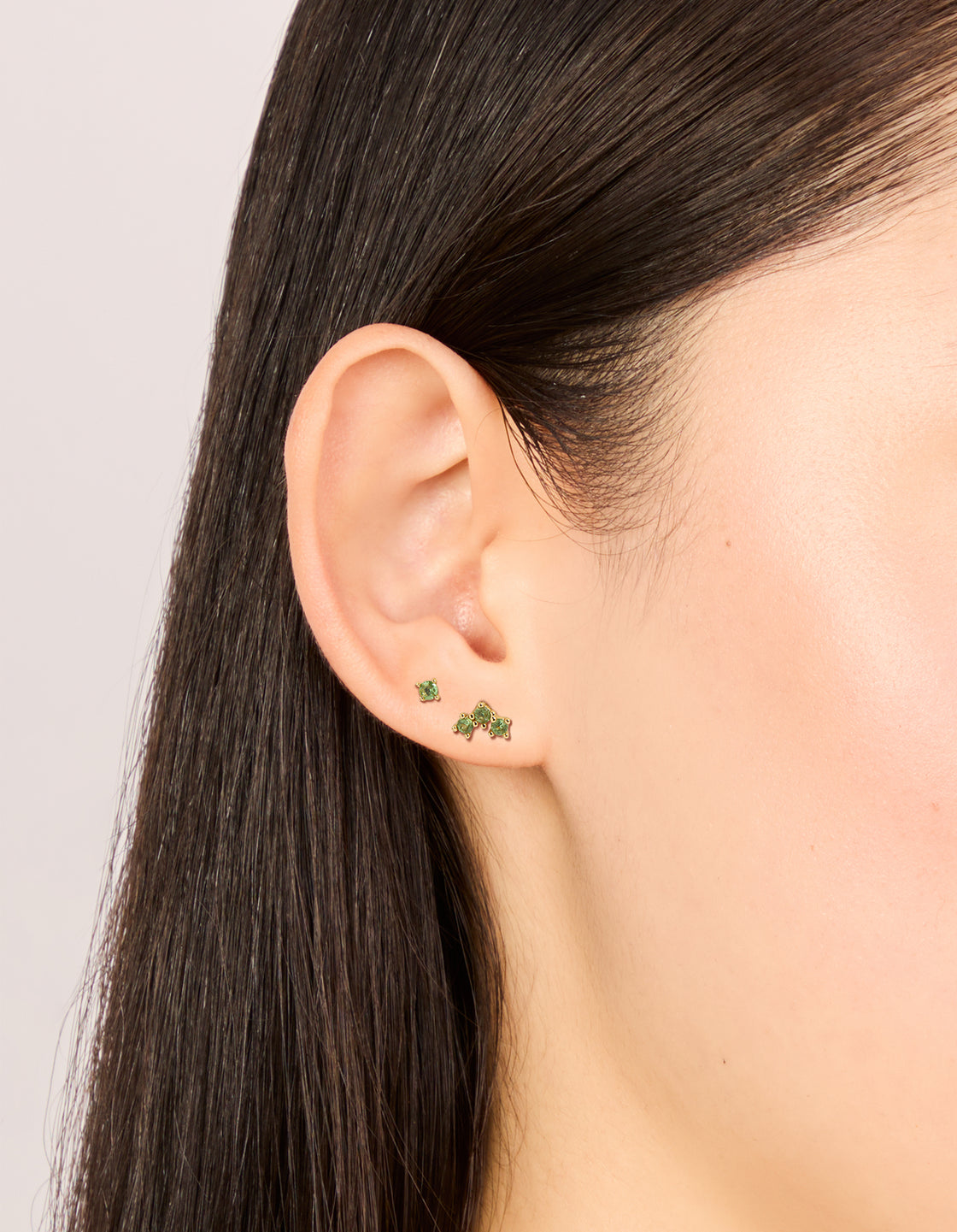 Featuring gold plated titanium olive green cubic zirconia flat back studs on ear view