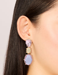 Featuring statement drop earrings with oval cut stones in purple and orange hues set in gold on ear view - link has visual effect only
