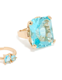 Featuring clear and blue oversized diamante rings in gold with oval stone cut, chunky statement style close up view - link has visual effect only