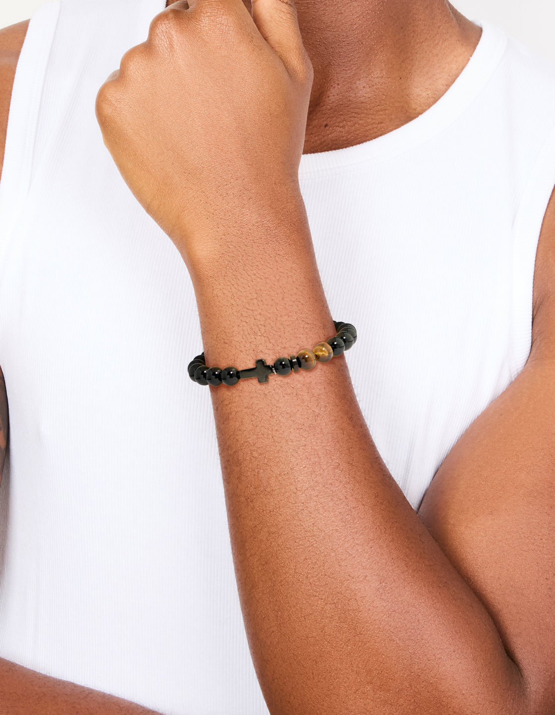 Crafted from waterproof black coated stainless steel, this mens beaded cross bracelet with tigers eye semi stones on wrist view