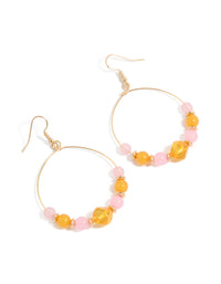 Showcasing statement drop earrings with round beads featuring textured light pink and orange details in gold front view - link has visual effect only