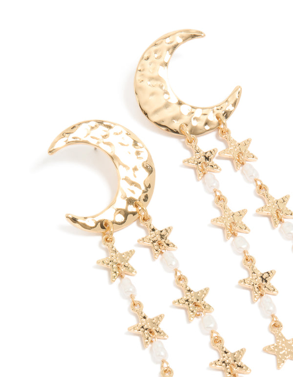 Showcasing gold crescent moon and star drop earrings with celestial charm details, pearl beads, and white accents close up view