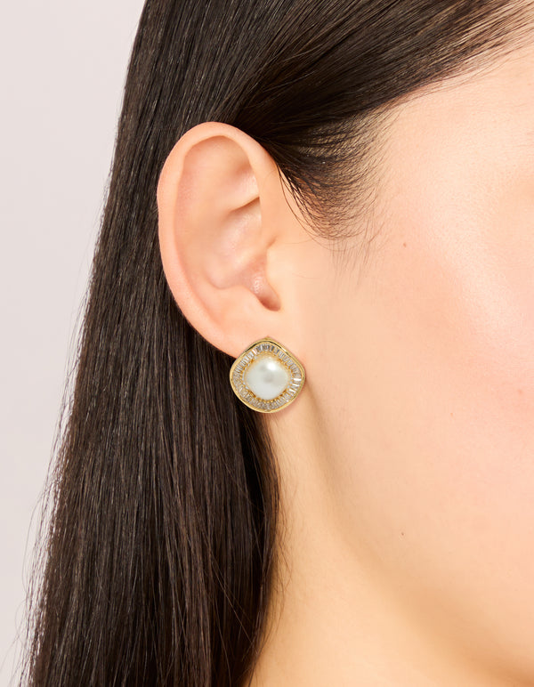Crafted from gold plated material, these cubic zirconia and pearl stud earrings are shown in an on ear view