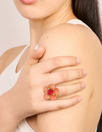Showcasing a statement pink stone flower ring in gold plated metal with light coral crimson accents on finger view - link has visual effect only