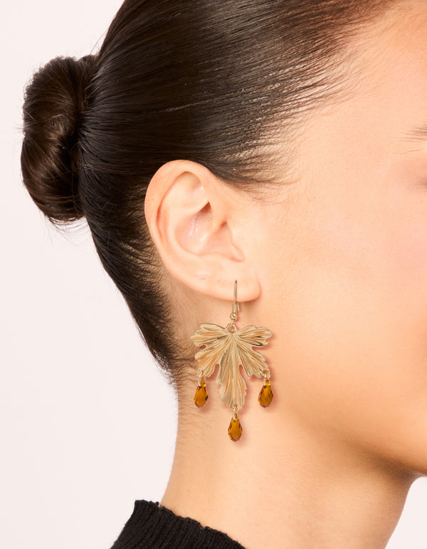 Discover statement drop earrings with floral leaf design featuring orange beads in gold on ear view
