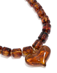Featuring a brown square bead and heart necklace with statement in gold tones close up view - link has visual effect only