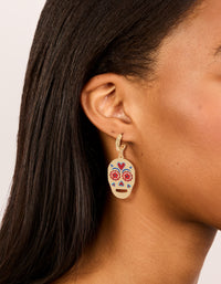Shop these gold fun skull drop earrings with floral and heart accents on ear view - link has visual effect only