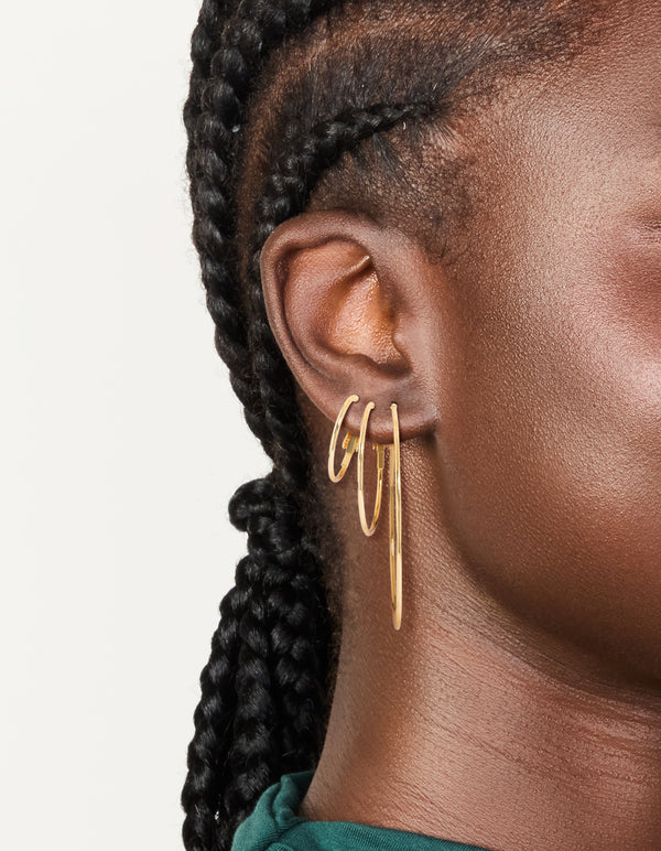 Featuring waterproof gold plated stainless steel extra thin hoop earrings in a 3-pack with closure and gold color on ear view
