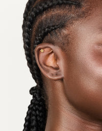 Showcasing this dainty cubic zirconia layered flower single flat back stud with titanium construction in gold plated finish and clear gemstones on ear view - link has visual effect only